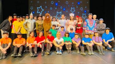 JVH "OZ" cast Students in colourful t-shirts sitting and standing as part of the cast of a school production of "OZ"